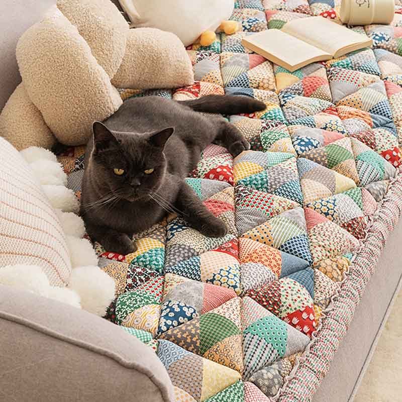 Grey cat resting on a colorful Triangle Patchwork quilted sofa mat