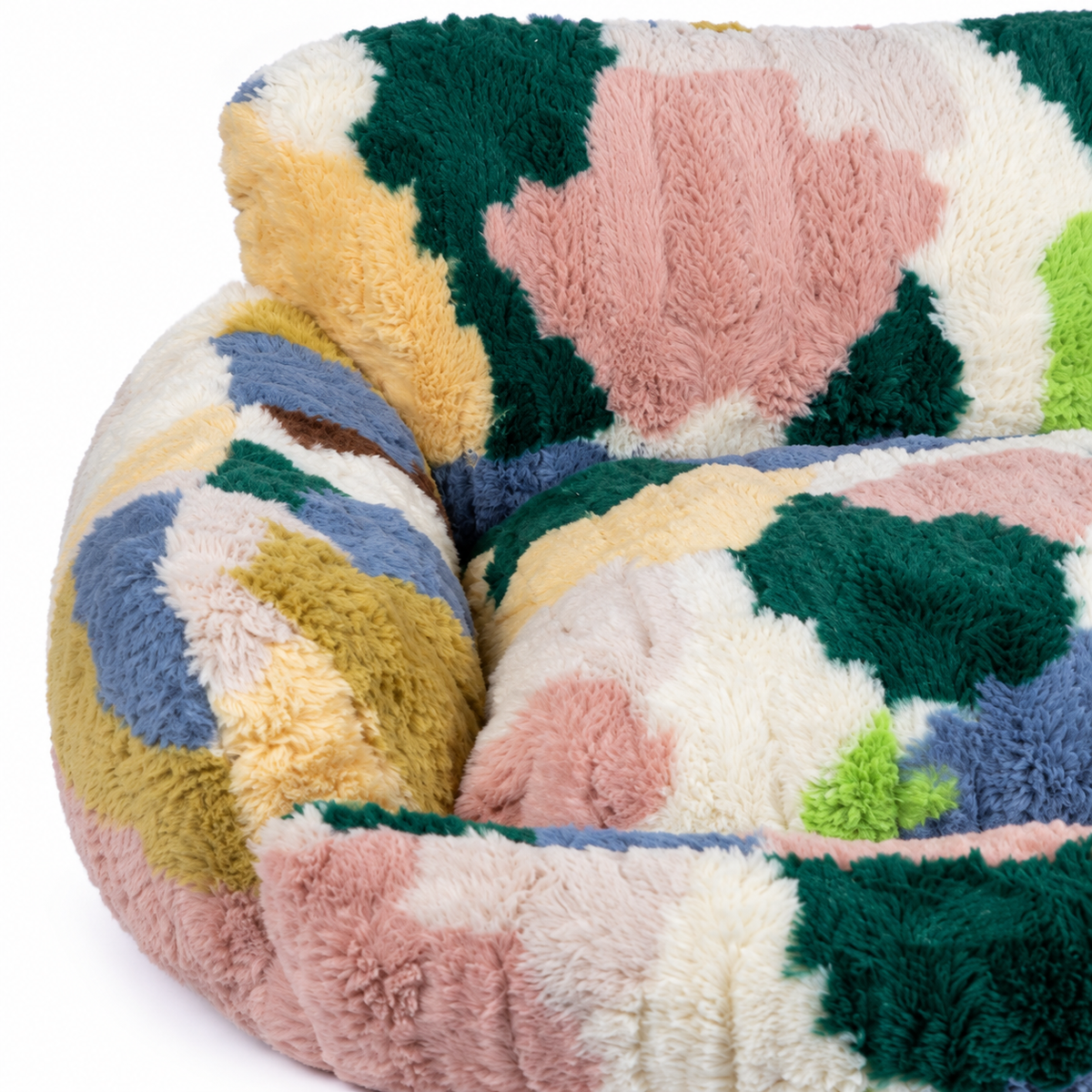 Detail of the multicolor plush pet nest's rounded side bolster meeting the raised padded backrest.